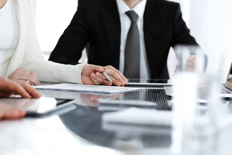 A group of business professionals engaged in a collaborative discussion about a contract during a meeting.